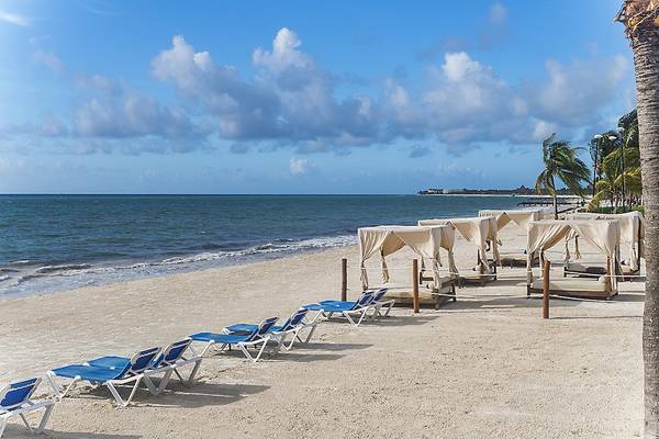 Strand des Ocean Maya Royale Hotels mit weißen Sonnenliegen und Vorhängen