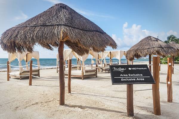 Exklusive Strandbereich im Ocean Maya Royale Hotel mit Liegebetten und Sonnenschirmen.