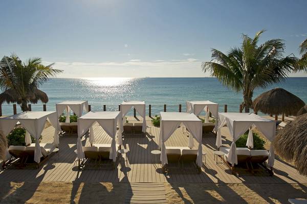 Außenbereich des Ocean Maya Royale Hotels mit Lounge-Betten und Palmen am Strand