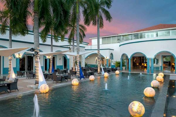 Außenbereich des Ocean Maya Royale Hotels mit Pool und Palmen bei Sonnenuntergang.