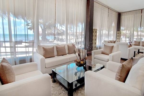 Hotellobby des Ocean Maya Royale mit weißen Möbeln und Blick auf den Strand.