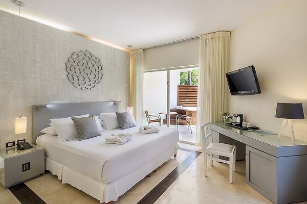 Innenansicht eines Hotelzimmers im Ocean Maya Royale mit Bett, Schreibtisch und Terrasse
