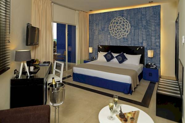 Hotelzimmer im Ocean Maya Royale mit Blick auf das Meer, Bett, Schreibtisch und Balkon.