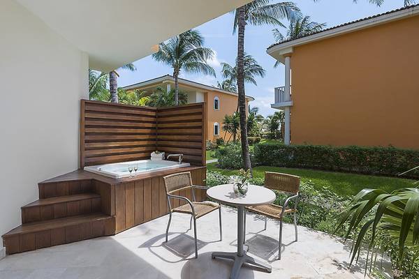 Terrasse des Ocean Maya Royale Hotels mit Jacuzzi und Tisch, umgeben von Gärten und Gebäuden.
