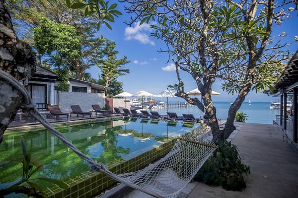 Poolbereich des Punnpreeda Beach Resorts mit Liegestühlen und Sonnenschirmen am Meer.