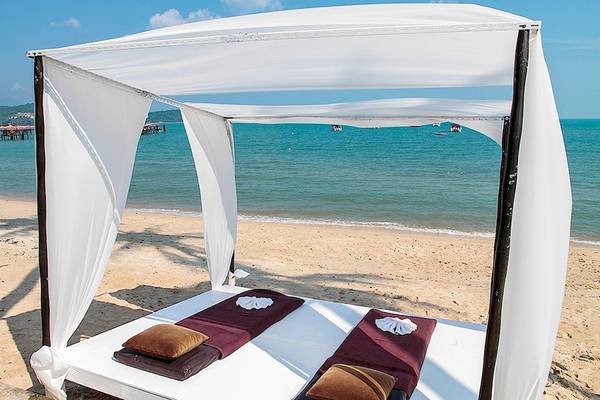 Ein Bett auf dem Strand unter einem Baldachin mit Blick auf das Meer.