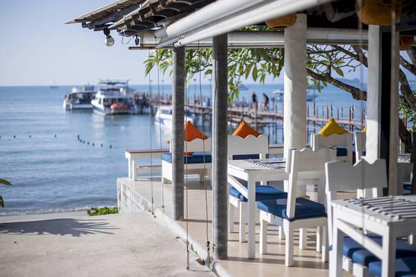 Außenbereich des Punnpreeda Beach Resorts mit Tischen und Stühlen am Meer.