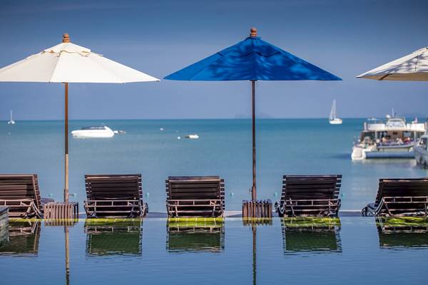 Pool mit Sonnenliegen und Umbrellas am Punnpreeda Beach Resort mit Blick auf das Meer und Boote
