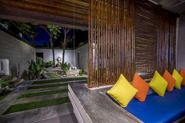 Atrium im Punnpreeda Beach Resort mit grünem Rasen, bunten Kissen und Bambuswänden
