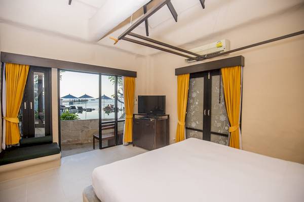 Zimmer im Punnpreeda Beach Resort mit Meerblick, Bett, Fernseher und offenem Balkon.