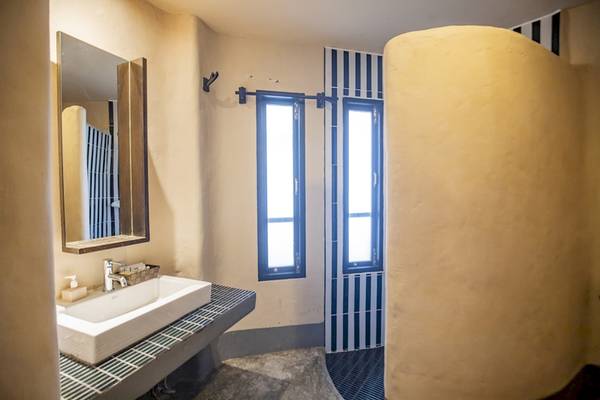 Badezimmer des Punnpreeda Beach Resort mit Waschbecken, Spiegel und Dusche.