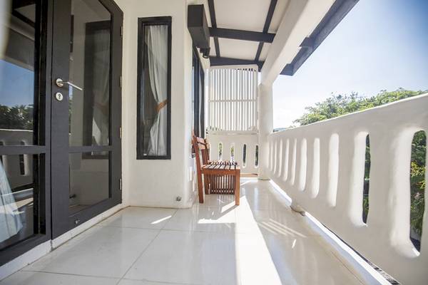 Der Balkon des Punnpreeda Beach Resorts mit einer Holzbank und einer Glastür.