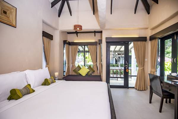 Schlafzimmer im Punnpreeda Beach Resort mit Doppelbett, Fenstern und Terrasse.