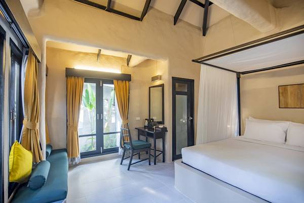 Innenansicht eines Zimmers im Punnpreeda Beach Resort mit einem Bett, Schreibtisch, Stuhl und Fenster.