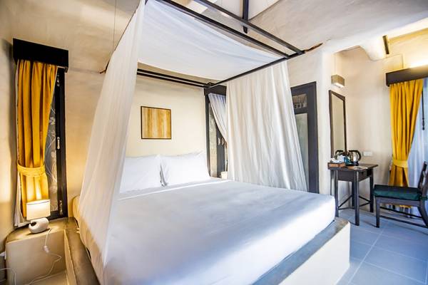 Bett mit Baldachin im Punnpreeda Beach Resort mit gelben Vorhängen und weißem Bettzeug.