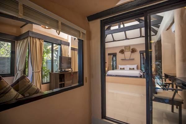 Ein Schlafzimmer mit einem großen Bett, Fernseher, und Möbeln im Punnpreeda Beach Resort.