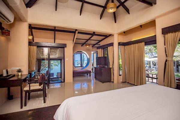 Innenansicht eines Zimmers im Punnpreeda Beach Resort mit Bett, Schreibtisch und Fenstern zum Meer.