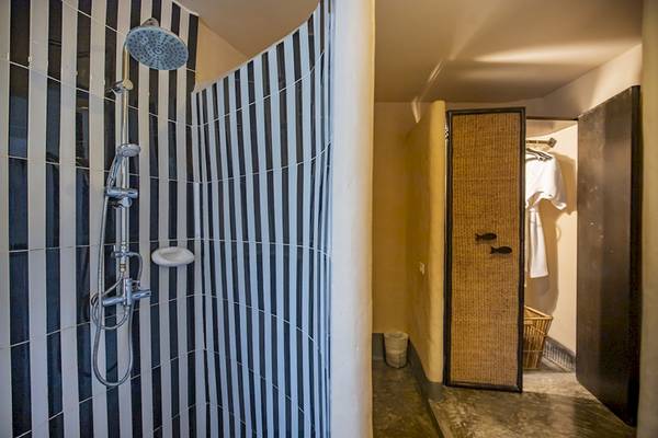 Dusche im Punnpreeda Beach Resort mit schwarzen und weißen Streifen und einer Kleiderstange.