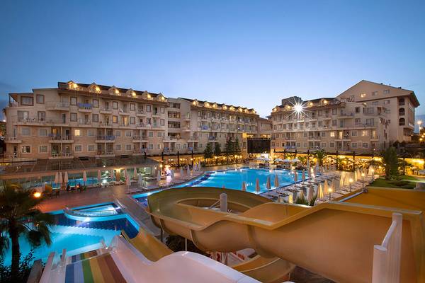 Abendliche Ansicht des Side Aluna Hotels mit Swimmingpool und Wasserrutsche.