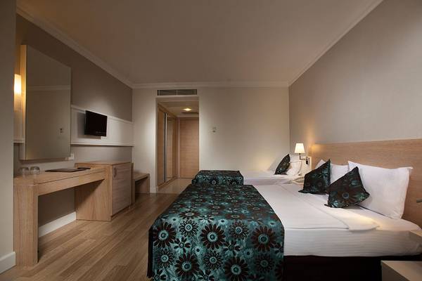 Innenansicht eines Hotelzimmers im Side Aluna Hotel mit zwei Betten, Dekor und Fernseher.