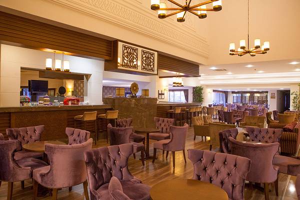 Loungebereich des Side Aluna Hotels mit vielen weichen Stühlen und Tischen, dekorativen Kronleuchtern und einer Theke.