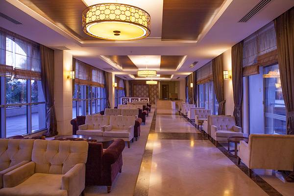 Innenansicht des Side Aluna Hotels mit gepolsterten Sofas und Tischen in der Lobbylounge.