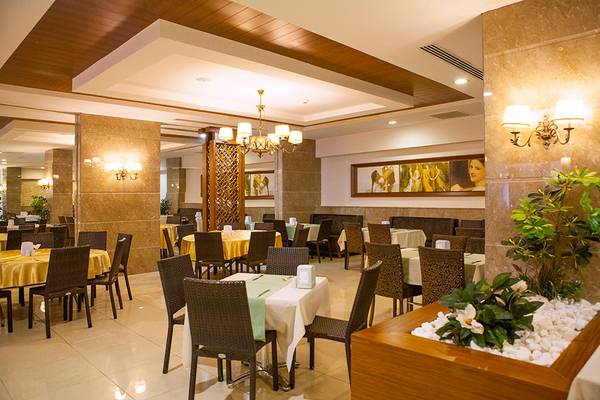 Innenansicht des Restaurants im Side Aluna Hotel mit gedeckten Tischen und Stühlen, Deckenlampe und Wandkunst.