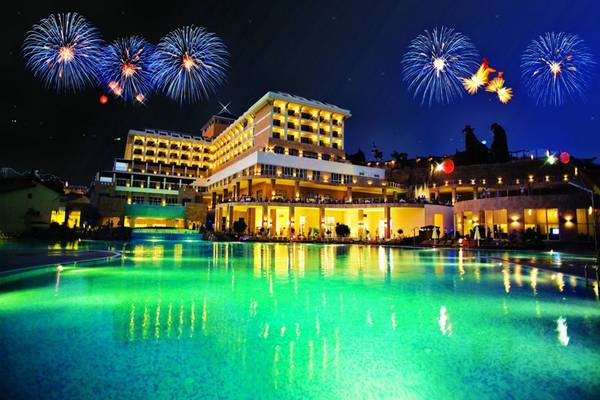 Das Horus Paradise Luxury Resort bei Nacht mit einem leuchtenden Pool und Feuerwerk am Himmel.