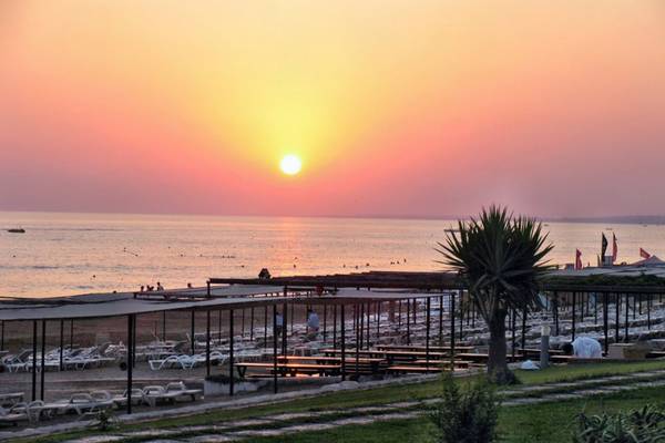 Sonnenuntergang am Strand des Horus Paradise Luxury Resort mit vielen Liegestühlen und Palmen