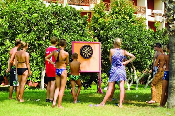 Gäste im Horus Paradise Luxury Resort werfen Darts auf einer Wiese neben Gebäuden