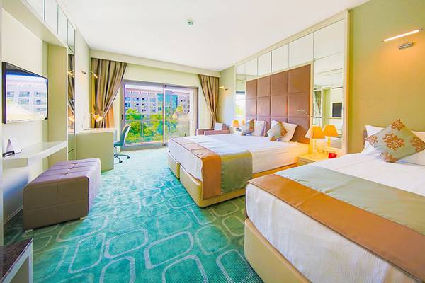 Zwei Doppelbetten in einem luxuriösen Zimmer im Horus Paradise Luxury Resort mit modernen Möbeln und einer Aussicht.