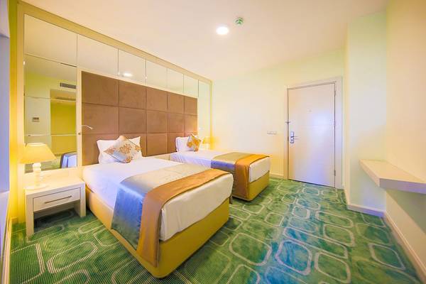 Doppelzimmer im Horus Paradise Luxury Resort mit zwei Betten, Nachttischen und einem großen Spiegel.