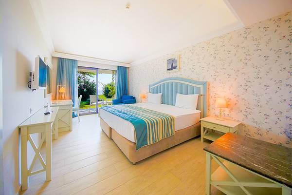 Innenansicht eines komfortablen Zimmers im Horus Paradise Luxury Resort mit Doppelbett, Fernseher und Schreibtisch.