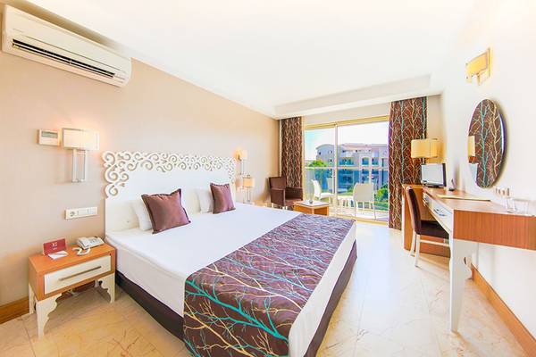 Hotelzimmer im Horus Paradise Luxury Resort mit Bett, Schreibtisch und Balkon.