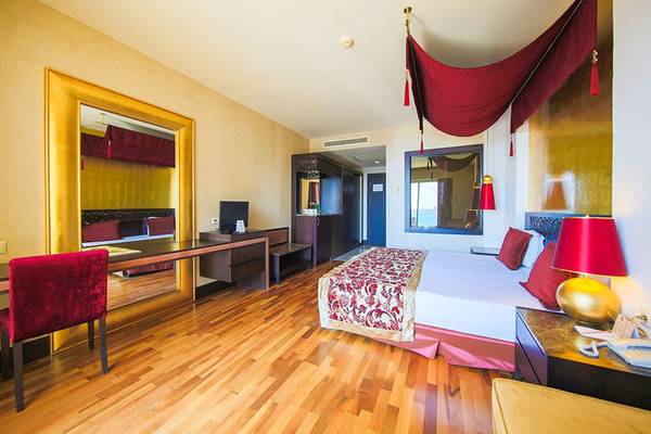 Innenansicht eines Hotelzimmers im Horus Paradise Luxury Resort mit Doppelbett, Schreibtisch und Spiegel.