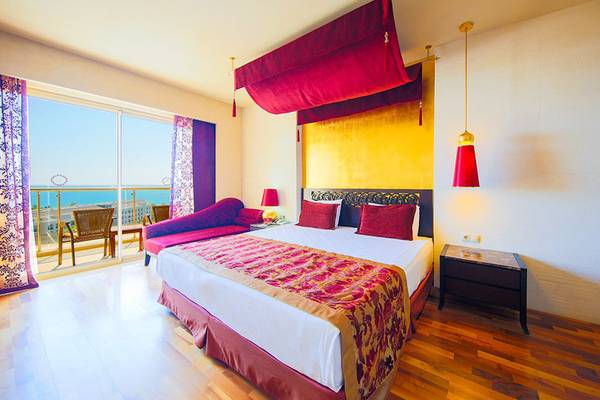 Luxuriöses Hotelzimmer im Horus Paradise Luxury Resort mit Meerblick, roter Dekoration und Holzboden.