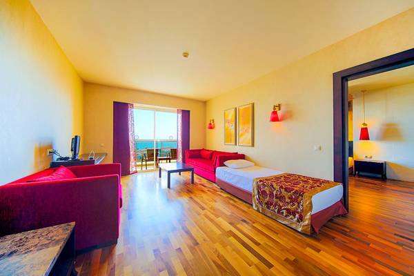 Innenansicht eines Hotelzimmers im Horus Paradise Luxury Resort mit Möbeln und Ausblick auf das Meer.