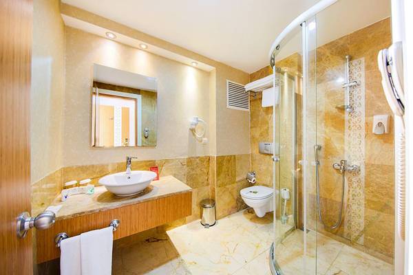 Badezimmer im Horus Paradise Luxury Resort mit Glasdusche, Waschbecken und Toilette.