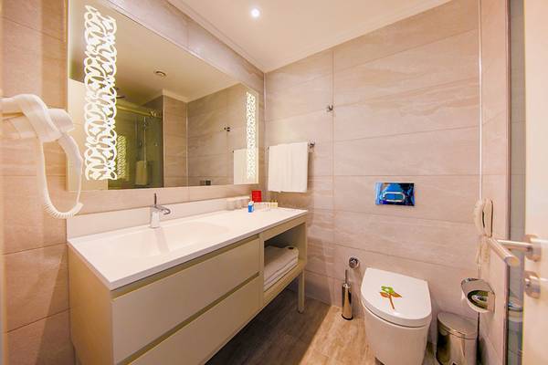 Badezimmer im Horus Paradise Luxury Resort mit Waschbecken, Spiegel und Toilette.