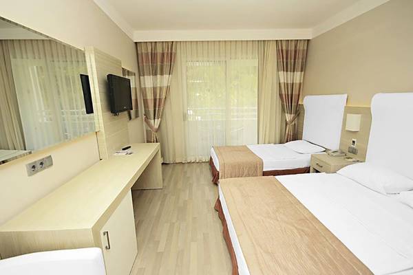 Doppelzimmer im Turunc Resort mit zwei Betten, Fernseher, Schreibtisch und Spiegel.