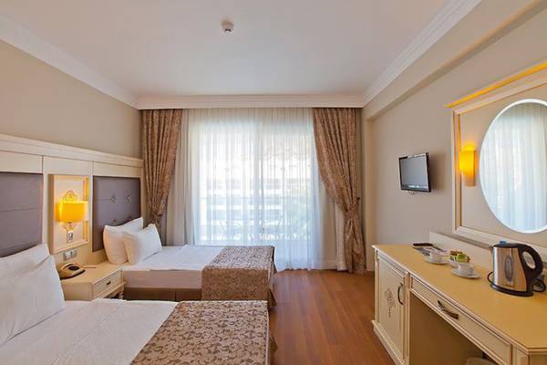 Doppelzimmer im Turunc Resort Hotel mit zwei Betten, Fernseher und Badezimmer.