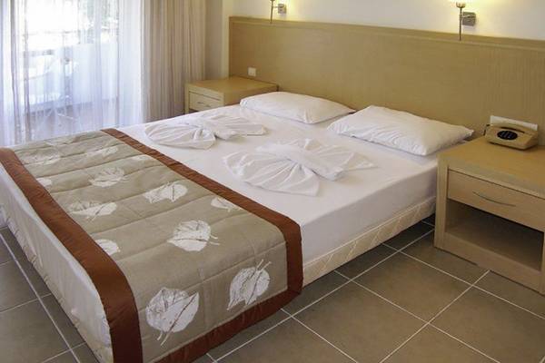 Hotelzimmer im Turunc Resort mit zwei Betten, Kissen und einem Telefon auf dem Nachttisch.