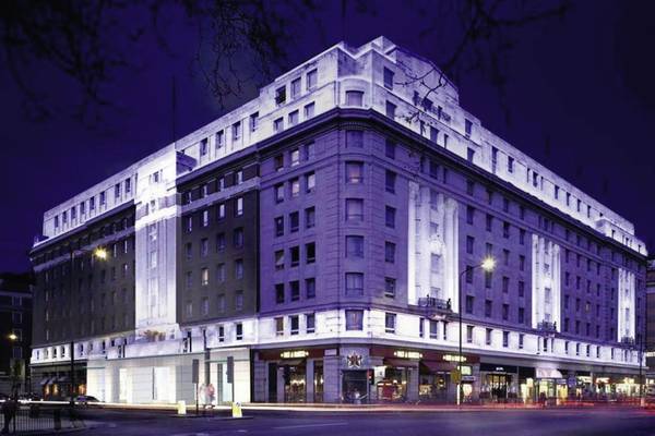 Außenansicht des Cumberland Hotels bei Nacht mit Beleuchtung und Passanten auf der Straße