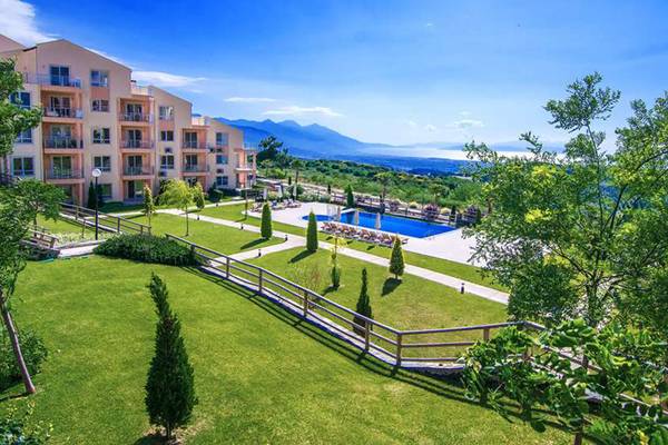 Außenansicht des Wyndham Residences Kusadasi Golf & Spa mit Swimmingpool und grüner Landschaft.