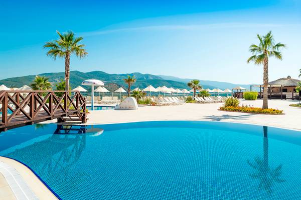 Außenpool des Wyndham Residences Kusadasi Golf & Spa mit Palmen und Liegestühlen