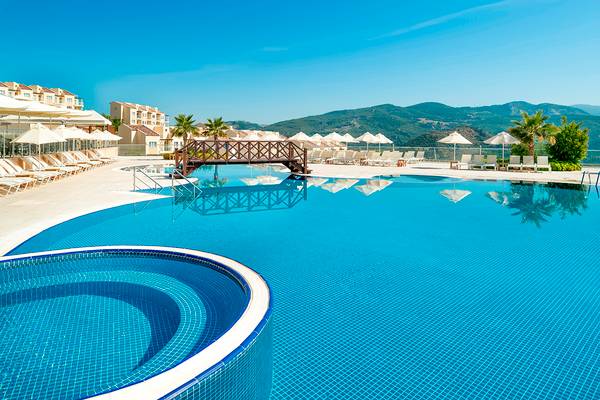 Außenbereich des Wyndham Residences Kusadasi Golf & Spa mit großem Pool, Sonnenliegen und Sonnenschirmen.