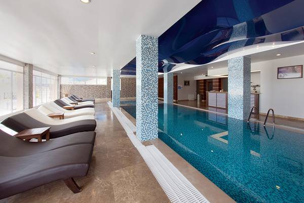 Innenpool des Wyndham Residences Kusadasi Golf & Spa mit blauer Decke und Liegestühlen