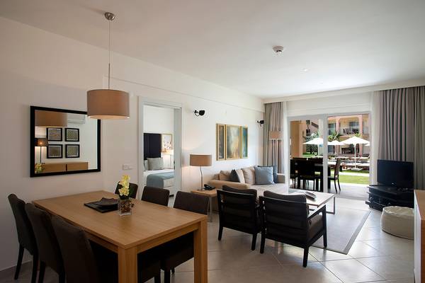 Wohnzimmer in Wyndham Residences Kusadasi Golf & Spa mit Esstisch, Sofa, Fernseher und Terrassenzugang