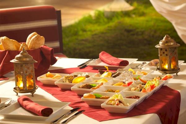 Speisetisch im Freien im El Mouradi Club Kantaoui mit verschiedenen Gerichten, Brot und Dekorationslampen.