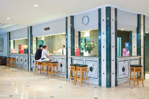 Empfangsbereich des El Mouradi Club Kantaoui mit drei Personen an der Rezeption.